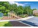 Community playground featuring a slide, climbing area, and wood-chip ground covering, next to a manicured lawn at 7524 Portbury Park Ln, Suwanee, GA 30024