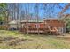 Sprawling backyard showcasing a deck, brick home, and a verdant lawn under a canopy of trees at 2447 Caladium Ne Dr, Atlanta, GA 30345