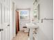 All-white bathroom featuring a unique pedestal sink, neutral tiling, and a window for natural light at 2447 Caladium Ne Dr, Atlanta, GA 30345