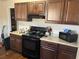 Functional kitchen with dark wood cabinets, granite countertops, and modern black appliances at 7977 Woods Ln, Jonesboro, GA 30236