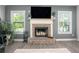 Close-up of a brick fireplace with a white mantle, flanked by windows and plants at 2106 Sycamore Ln, Loganville, GA 30052