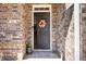 Close-up of the front door, showcasing a decorative wreath and welcome mat, set in a brick surround at 116 Holly View Ln, Canton, GA 30114