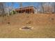 Hillside backyard with wooden deck and view of a custom fire pit surrounded by trees at 885 Malcom Rd, Covington, GA 30014
