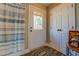 Bright bathroom showing the shower with blue striped curtain, wood-look flooring, and a full light door at 885 Malcom Rd, Covington, GA 30014