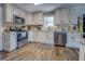 Well-lit kitchen featuring modern appliances, tile backsplash, wood-look flooring, and distressed white cabinetry at 885 Malcom Rd, Covington, GA 30014