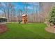 Spacious backyard features a wooden playset, lush green lawn and wooded backdrop at 1293 Wynford Colony Sw, Marietta, GA 30064