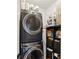 Modern laundry room with stacked washer and dryer, storage shelves, and cleaning supplies at 2828 Peachtree Nw Rd # 1701, Atlanta, GA 30305