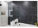 Modern shower with sleek black marble-patterned tiles, a tub, and a glass door at 2828 Peachtree Nw Rd # 1701, Atlanta, GA 30305