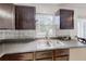 Kitchen featuring a stainless steel sink, dark cabinets, and decorative backsplash at 4422 Wellington Ter, Decatur, GA 30035