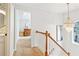 Hallway landing featuring a wooden railing and a beaded chandelier at 447 Hemlock Dr, Pine Lake, GA 30083