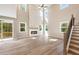 Sunlit living room with a stone fireplace, high ceilings, and light wood flooring at 2460 Hidden Creek Rd, Kennesaw, GA 30152