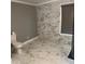 Well-lit bathroom featuring marble accent wall, marble flooring, toilet, and window with wood blinds at 471 Tipton Dr, Riverdale, GA 30274