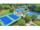 Aerial view of blue and green tennis courts with landscaping and lighting, perfect for a match at 3743 Heathermoor Ct, Dacula, GA 30019