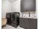 Laundry room with gray washer and dryer and white cabinets at 1290 Lupo Loop, Chattahoochee Hills, GA 30268