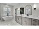 A bright bathroom features double sinks and arched mirrors, with a modern soaker tub near a window at 474 Maxwell Rd, Roswell, GA 30075