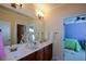 Bright bathroom featuring double sinks, a large mirror, and a doorway to the bedroom at 6026 Southland Dr, Stone Mountain, GA 30087