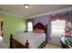 A charming bedroom featuring decorative windows, a wood bed frame, and multiple pastel accent colors at 6026 Southland Dr, Stone Mountain, GA 30087