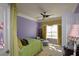 Cozy bedroom with green bedding, purple walls, a ceiling fan, and decorative window treatments at 6026 Southland Dr, Stone Mountain, GA 30087