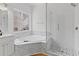 Bathroom featuring glass enclosed shower, a soaking tub with marble surround, and a single window above the tub at 1471 Adair Hill Ct, Dacula, GA 30019