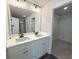 Bathroom with double sinks, white cabinets, large mirror, and access to the walk-in closet at 5447 Blossomwood Sw Trl, Mableton, GA 30126