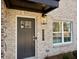 Charming front entrance featuring a gray painted door, modern lighting, and a freshly painted light brick facade at 5447 Blossomwood Sw Trl, Mableton, GA 30126