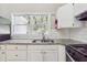 A bright kitchen boasts granite countertops, white cabinets, stainless sink with an outdoor view through a window at 3035 Mclendon Nw Cir, Atlanta, GA 30318