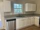 Well-lit kitchen featuring white cabinets, granite countertops, and a stainless steel dishwasher at 2678 Brook Park Way, Atlanta, GA 30340