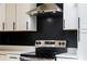 Stainless steel range and hood in kitchen with white cabinets, quartz countertops and black backsplash at 526 Myrtle St, Villa Rica, GA 30180