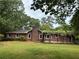 Exterior view of a single-story brick home with red shutters surrounded by lush greenery at 308 Tulipwood Sw Cir, Conyers, GA 30094