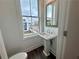 Well-lit powder room features a pedestal sink, mirror, and window with views of the neighborhood at 532 Healy Dr # 61, Cumming, GA 30040