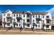 View of newly-constructed townhomes with white painted brick, dark accents, and manicured lawns at 532 Healy Dr # 61, Cumming, GA 30040