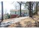 Exterior view of the light blue home showcasing brick foundation, multiple windows, driveway, and mature trees at 5087 Fairmont Se Rd, Smyrna, GA 30082