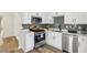 Updated kitchen features stainless steel appliances, white cabinets, modern backsplash, and luxury vinyl flooring at 1069 Falling Water Se Dr, Smyrna, GA 30080