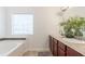 Bright bathroom featuring double sinks, granite countertops, a soaking tub, and a large window at 6945 Merrywood Dr, Fairburn, GA 30213