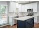 Modern kitchen featuring white cabinetry, stainless steel appliances, an island, and hardwood floors at 6815 Fairgreen Dr, Suwanee, GA 30024