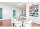 Elegant dining room with a glass table, white chairs, hardwood floors, a modern light fixture, and colorful artwork at 45 Ivan Allen Jr Nw Blvd # 1908, Atlanta, GA 30308