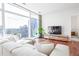 Bright living room with a white sofa, wood floors, a large window showing city views, and a modern entertainment center at 45 Ivan Allen Jr Nw Blvd # 1908, Atlanta, GA 30308