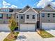 A view of the townhouse featuring a gray brick exterior, two-car garage, and freshly landscaped front yard at 1312 Fern Ridge Ct # 78, Norcross, GA 30093