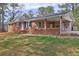 Charming brick home with a covered porch and carport, surrounded by mature trees and a well-maintained lawn at 2924 Vogue Dr, Douglasville, GA 30134