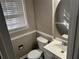 Well-lit half bathroom with white fixtures, paneled walls and a round decorative mirror at 4502 Cherie Glen Trl, Stone Mountain, GA 30083