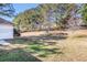 View of the spacious backyard with a border of mature trees and an unkept lawn at 11941 Fairway Overlook, Fayetteville, GA 30215