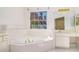 Bright bathroom with a large soaking tub, tile surround, white vanity, and large window at 11941 Fairway Overlook, Fayetteville, GA 30215