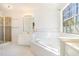Bright bathroom featuring a large soaking tub with tile surround, glass shower, and double sink vanity at 11941 Fairway Overlook, Fayetteville, GA 30215