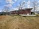 View of a backyard showing a brick house, dry grass, and tree stumps at 1742 Mural Dr, Morrow, GA 30260