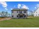 Rear view of a two-story home with a spacious backyard and a covered patio area at 7685 Homer Dr, Cumming, GA 30028