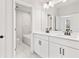 Modern bathroom featuring double vanity with white cabinets, black hardware, and a marble-tiled shower/tub at 7685 Homer Dr, Cumming, GA 30028