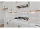 Close-up of a stylish kitchen featuring white cabinets, quartz countertops, and a built-in gas cooktop at 7685 Homer Dr, Cumming, GA 30028