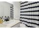 A bright bathroom features a white sink, toilet, mirror, and a blue and white striped shower curtain at 4053 Overland Trl, Snellville, GA 30039