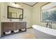 Elegant bathroom featuring a soaking tub, dual vanity with marble countertop, and natural light at 136 Huntcliff Trl, Ellenwood, GA 30294