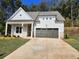 Charming single-Gathering home featuring light gray siding, white trim, a covered porch, and an attached two-car garage at 3032 Farm Tract Trl, Woodstock, GA 30189